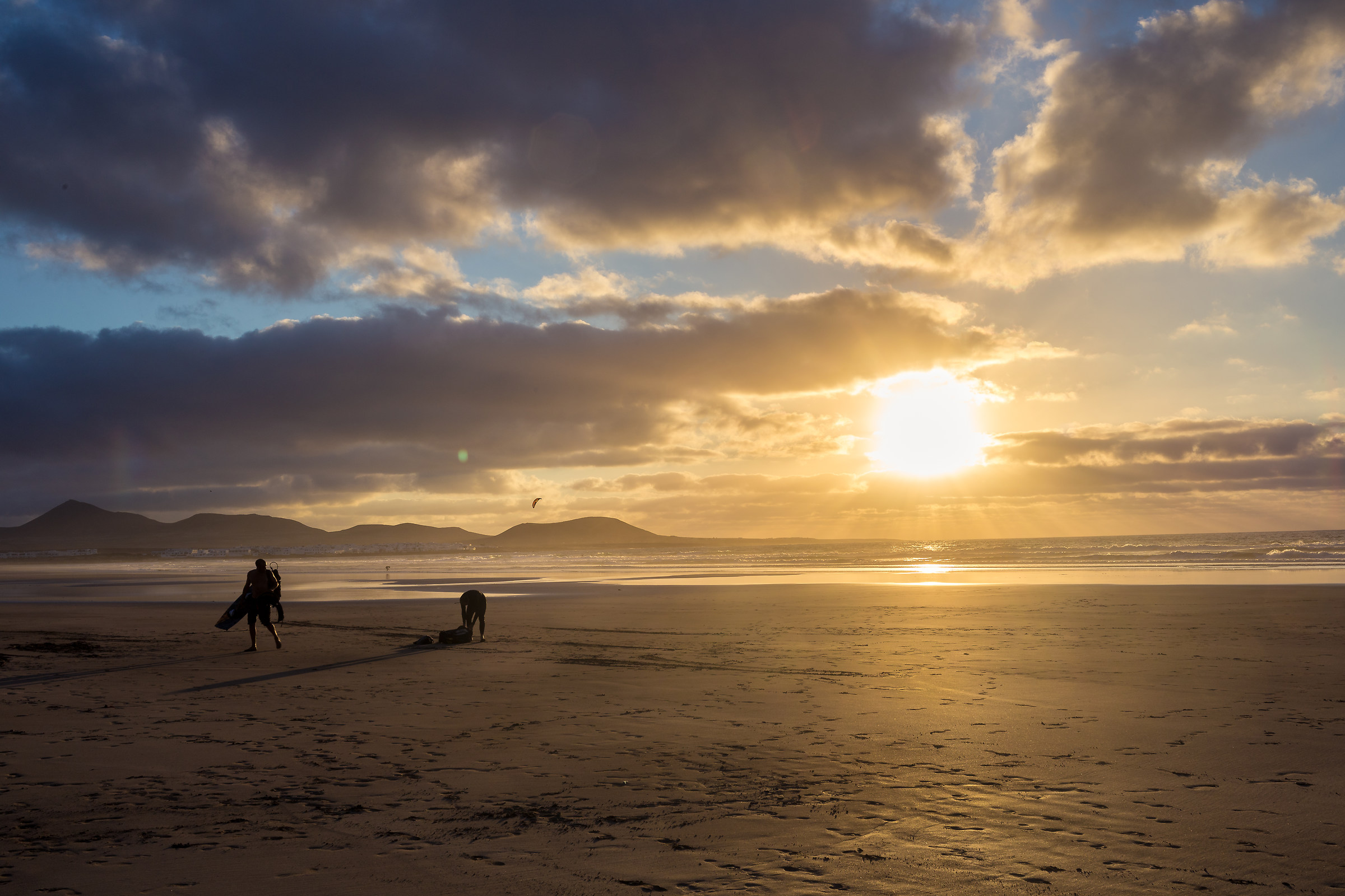Surfisti lasciano la spiaggia all'ultima luce