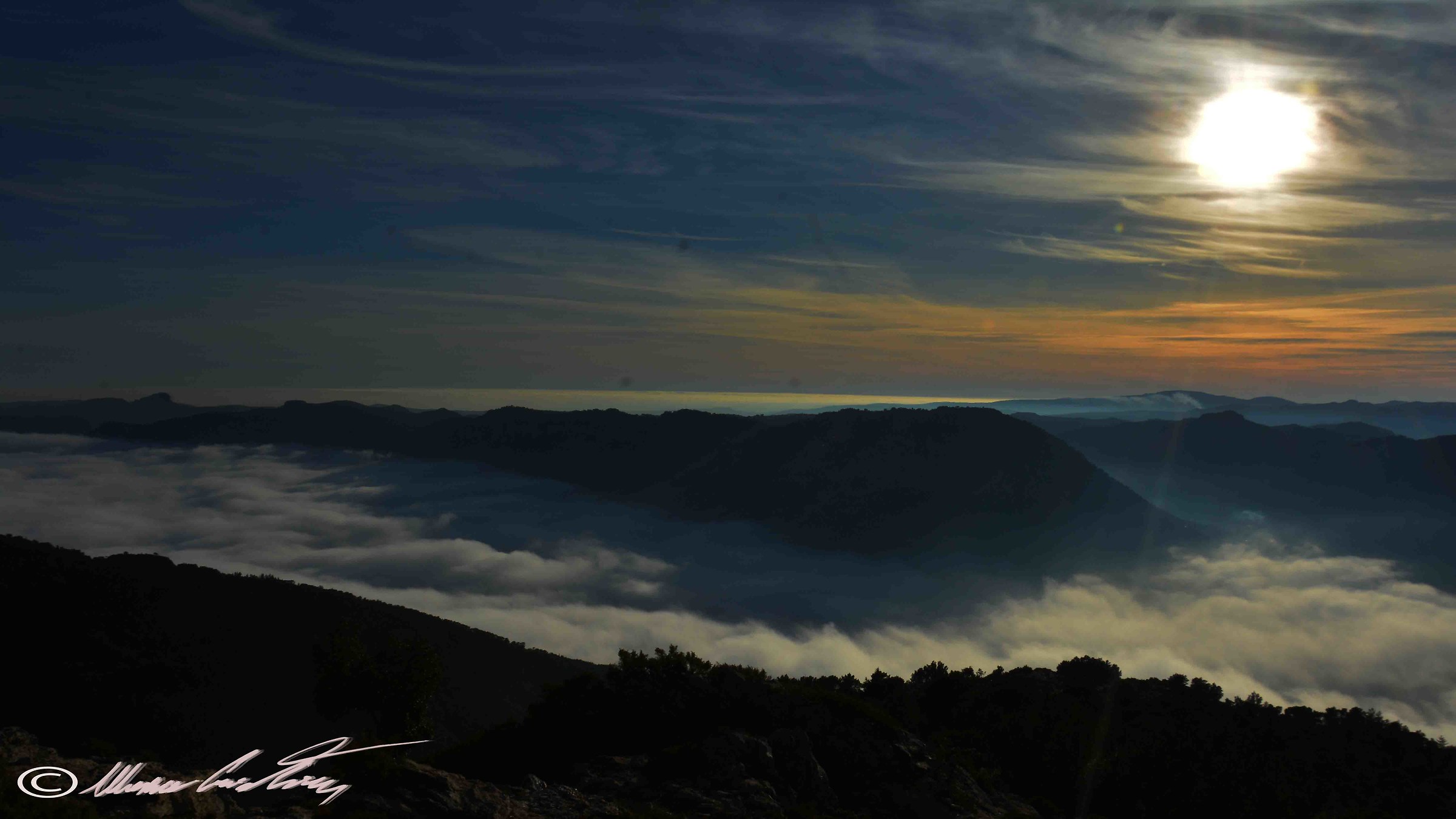 a sunset above the clouds that fill the valley of