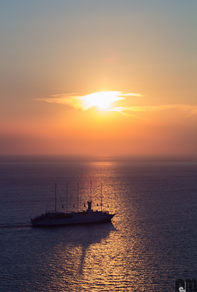Sunset (behind the cloud) photographed from Oia, Santori