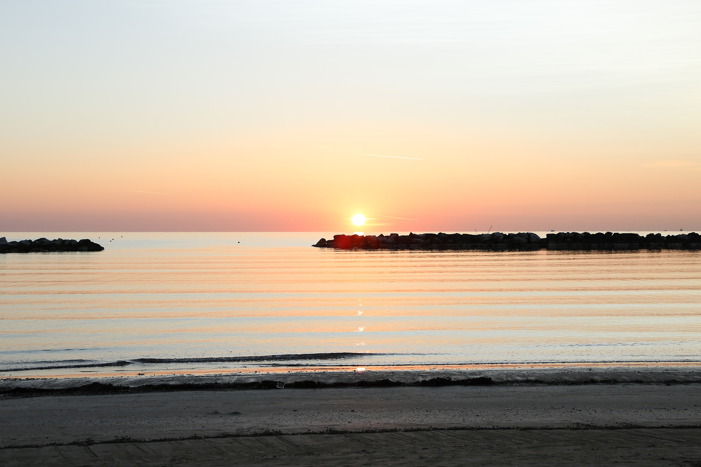 il sole sorge sulla spiaggia di rimini