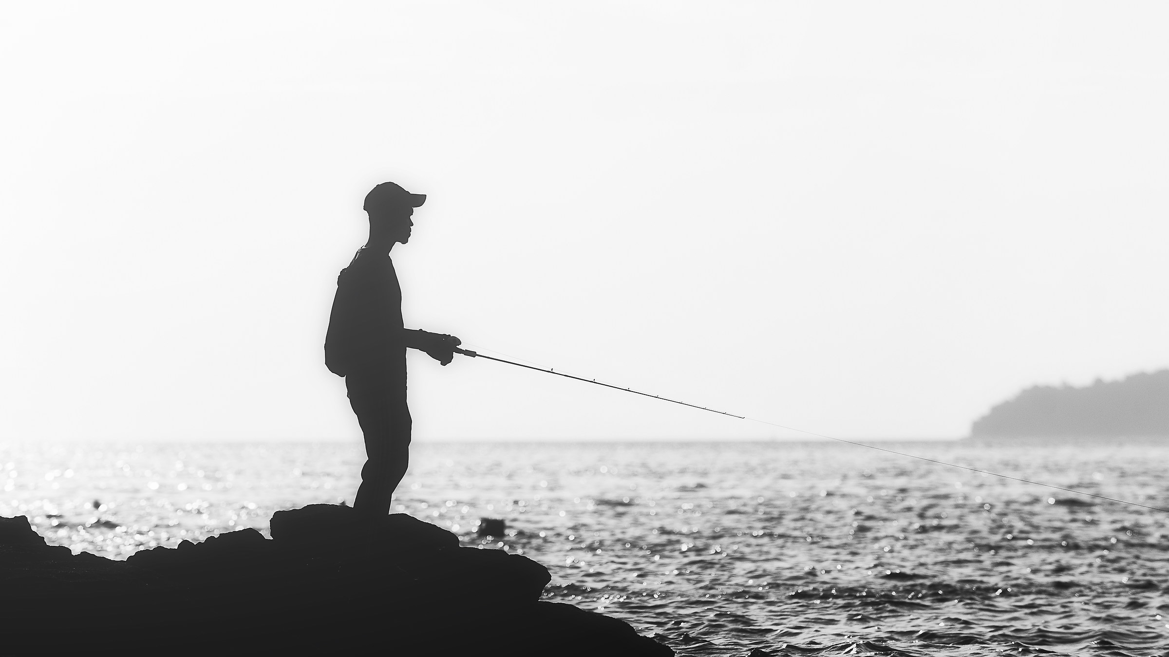 Siluetta dell'uomo che pesca sulla spiaggia.