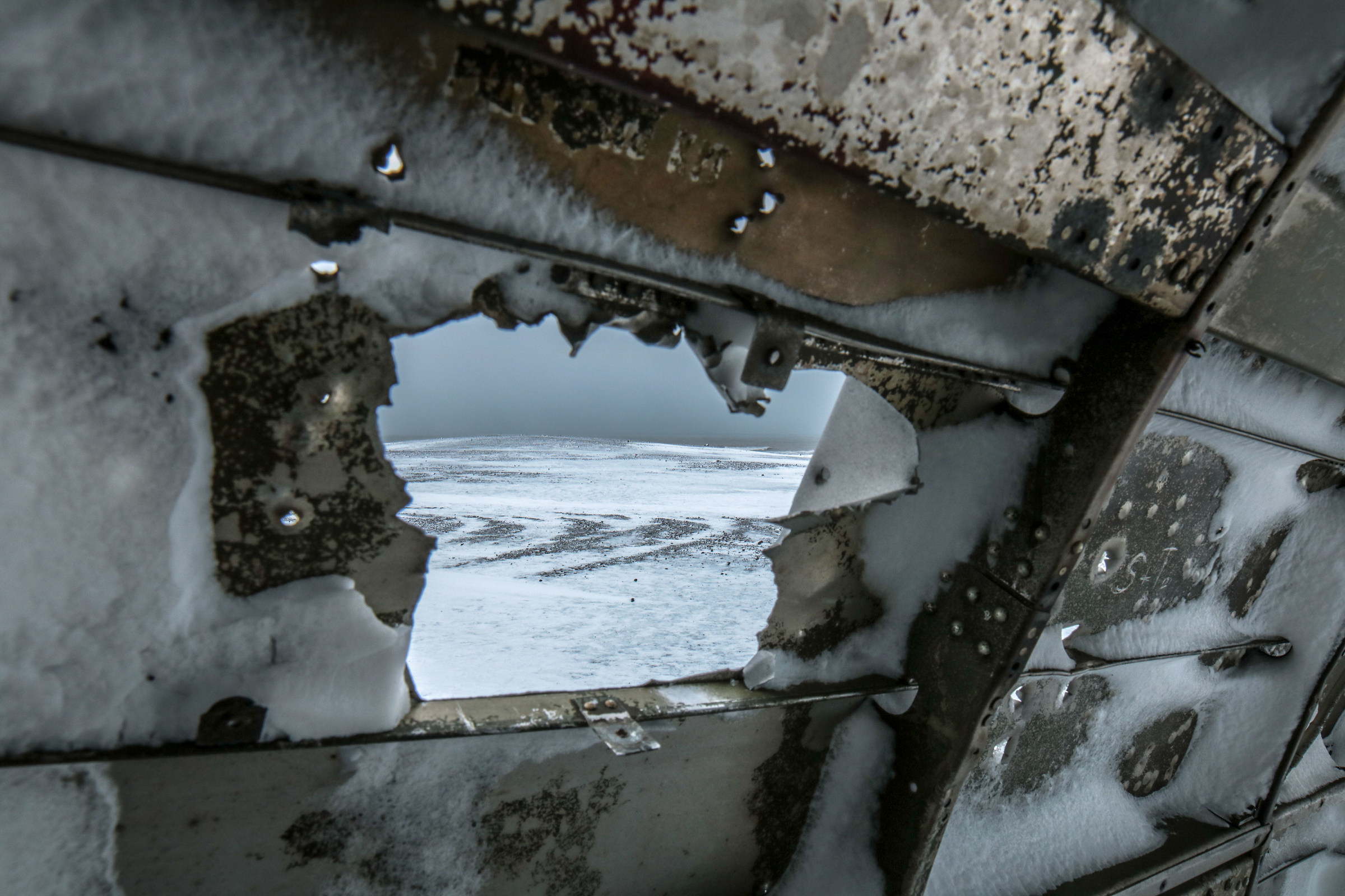 Scorcio della spiaggia innevata dal relitto di un aereo