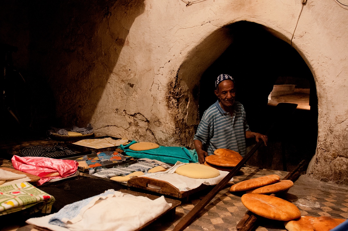Baker bakes bread in the oven to local Riad Zitoun