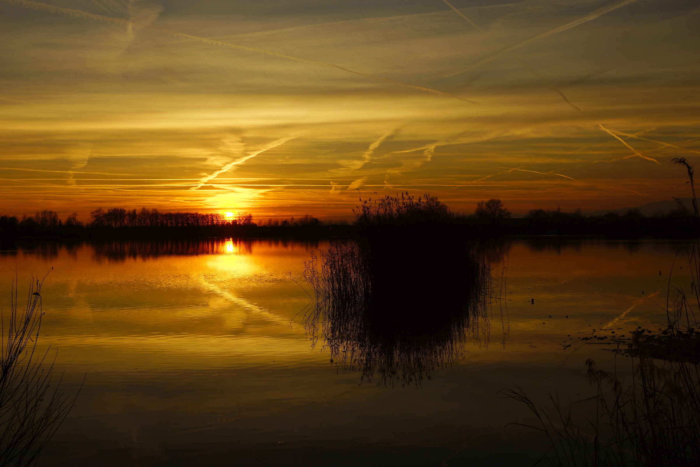 Sunset on the lake and trails of airplanes