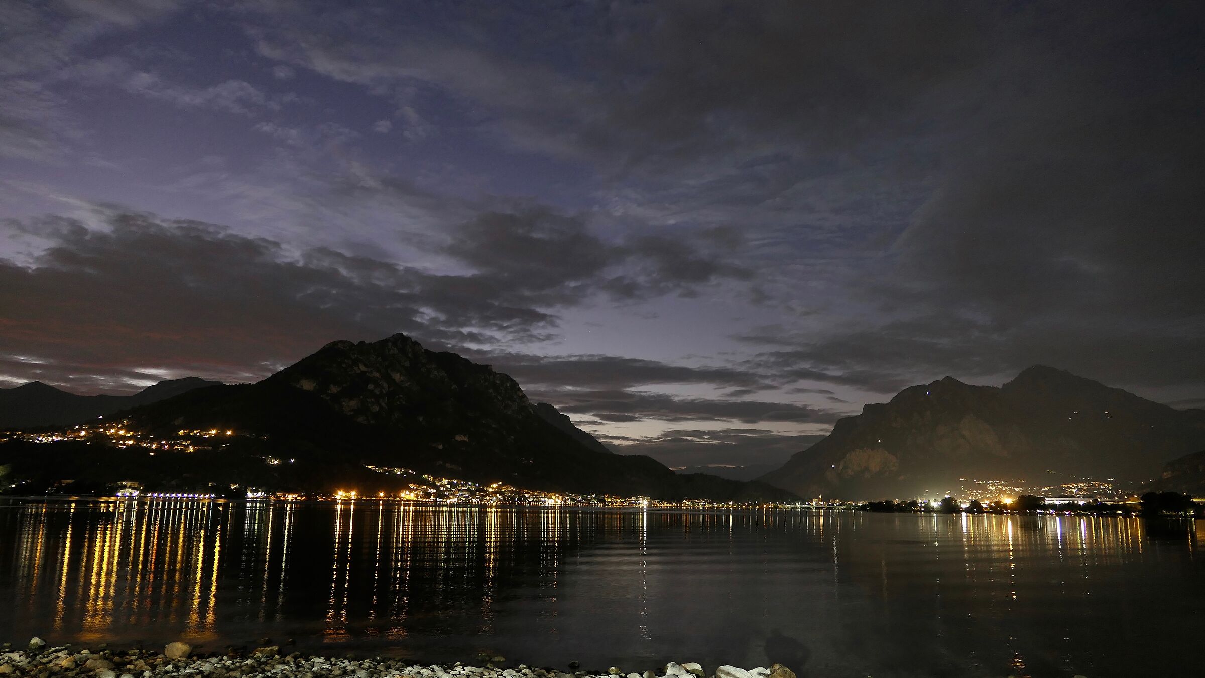 Lecco is reflected at dusk on Lake Garlate