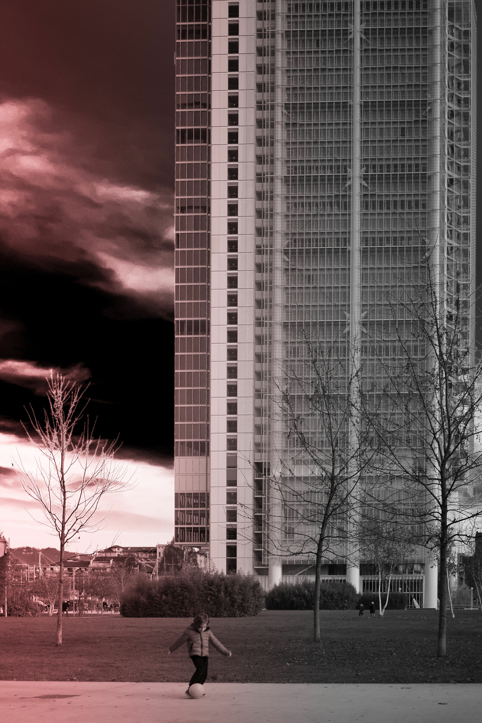 Child plays ball with skyscraper behind