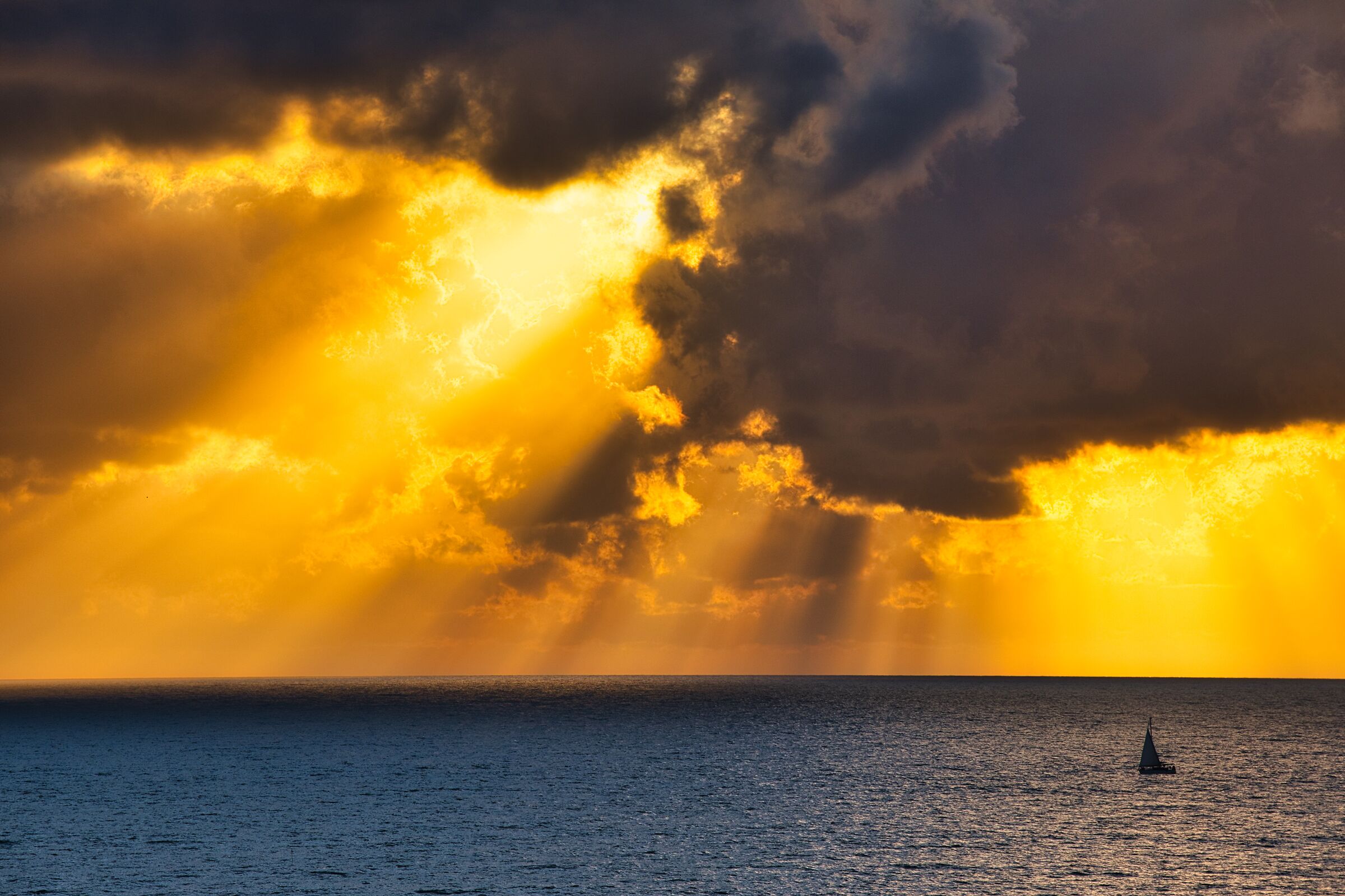 Sea at sunset, with clouds and sailboat