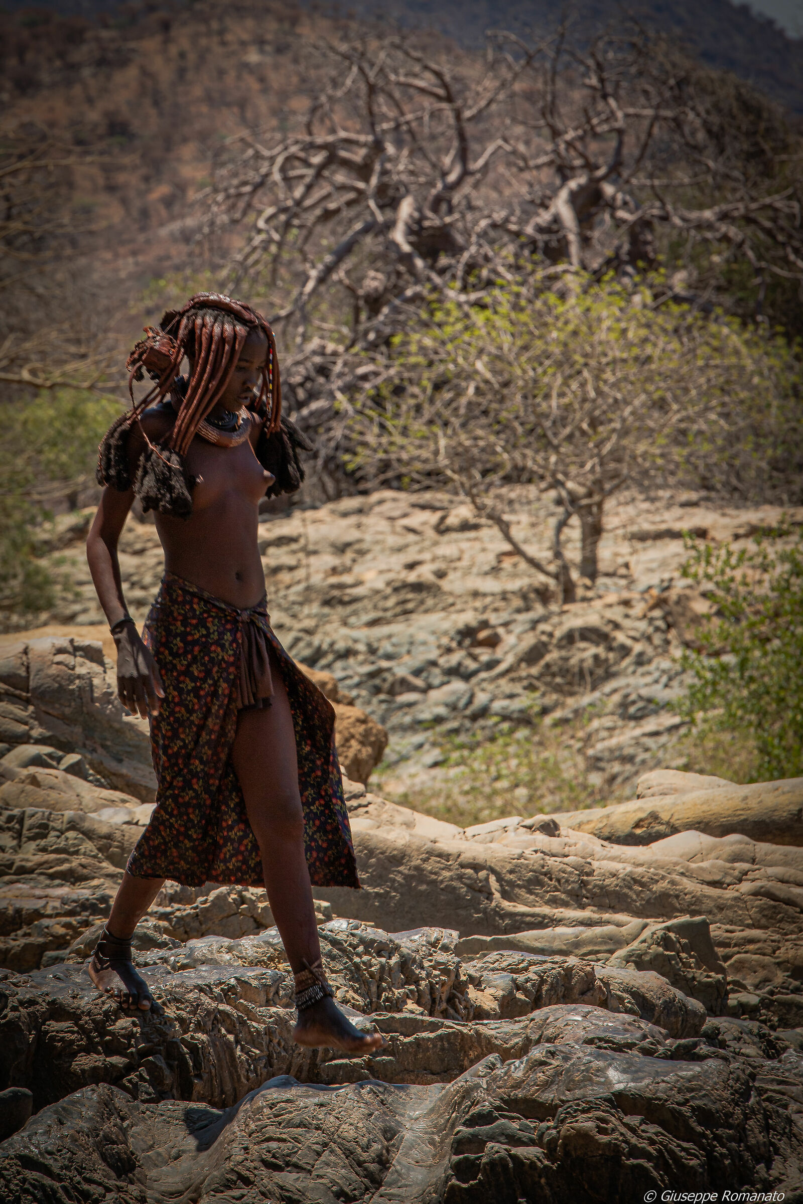 Popolo himba. Ragazza che cammina lungo il fiume