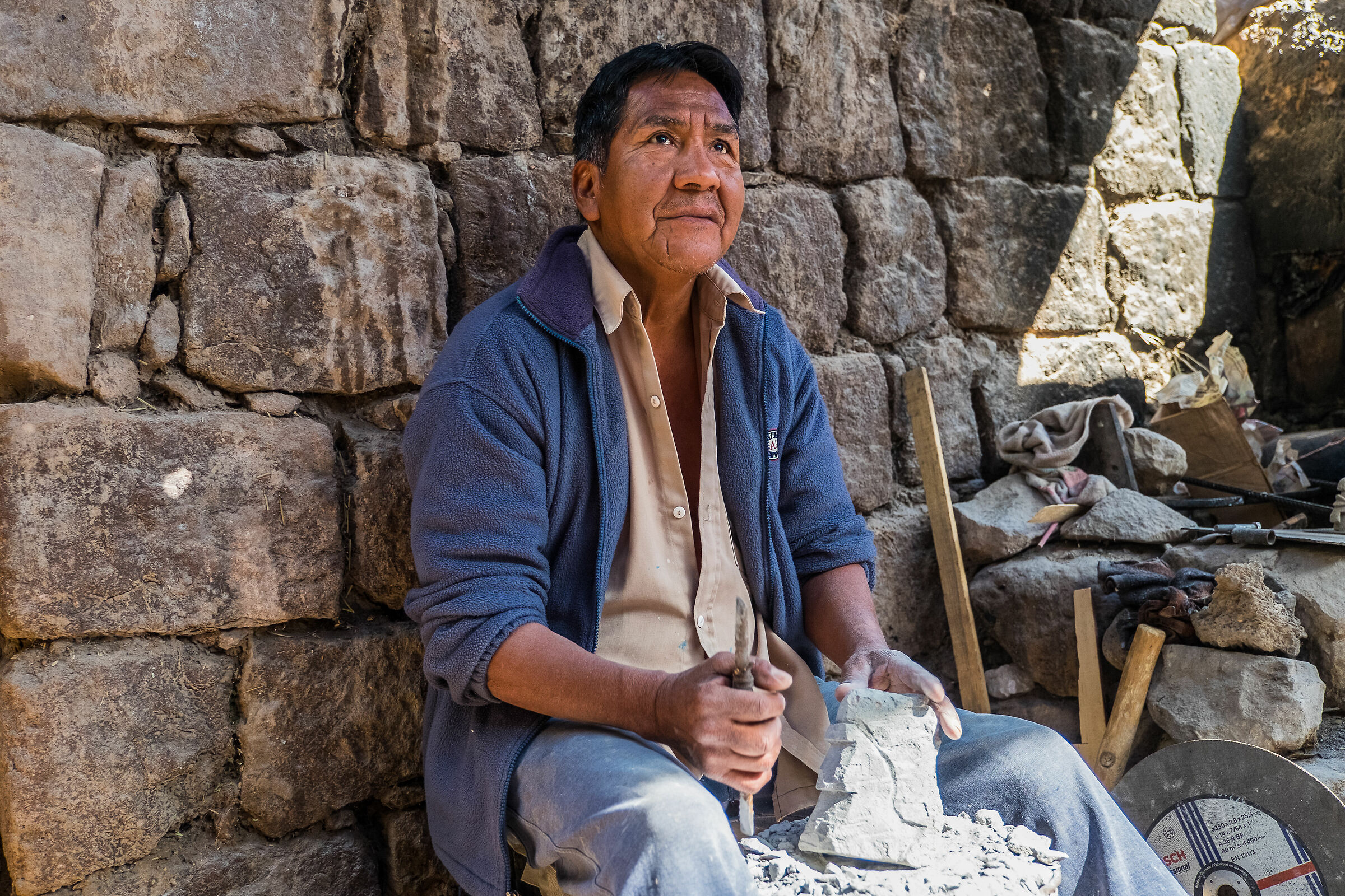 Sculptor of Andea rock between walls of adobe