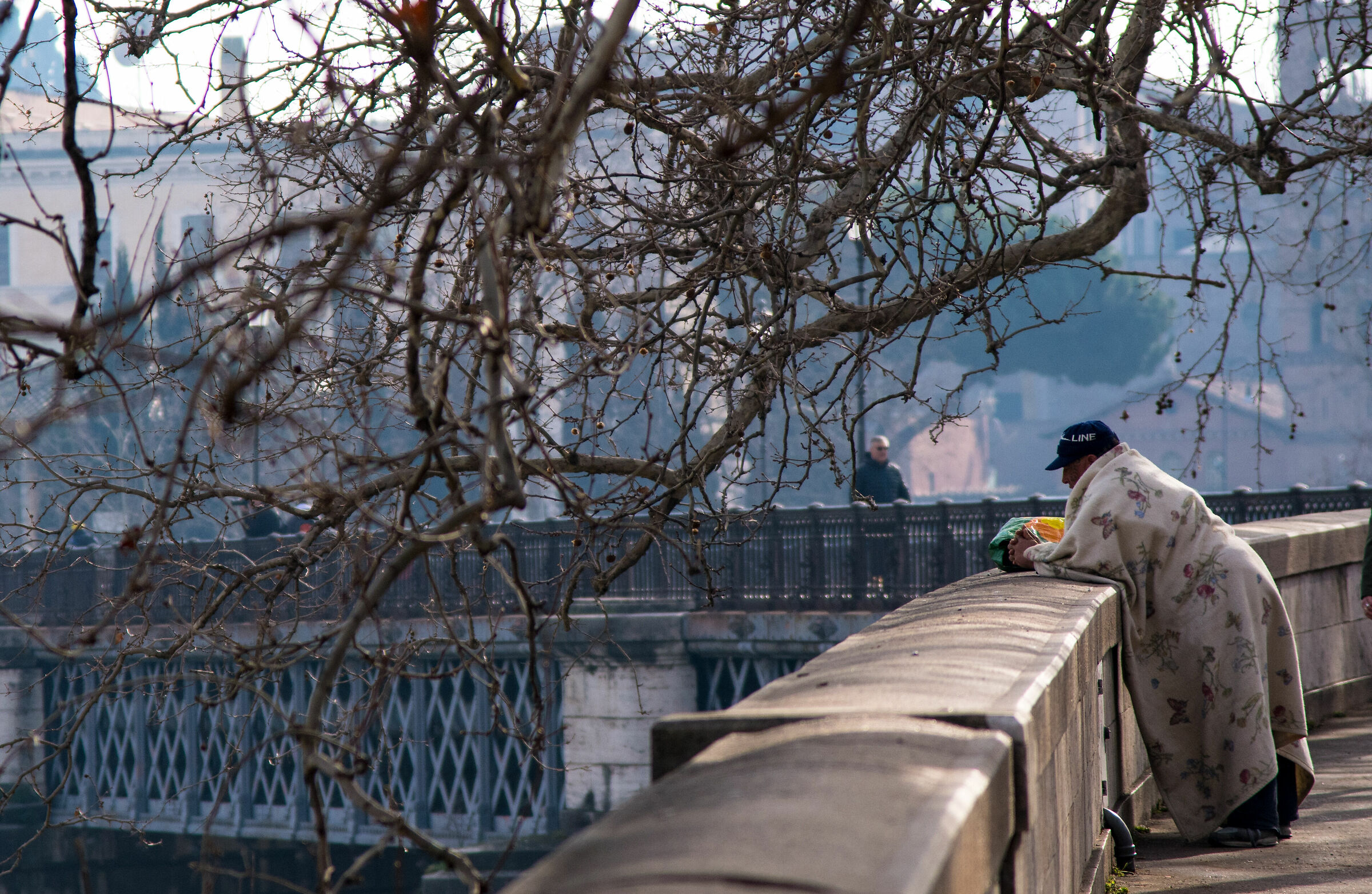 Un homeless avvolto in una coperta affacciato
