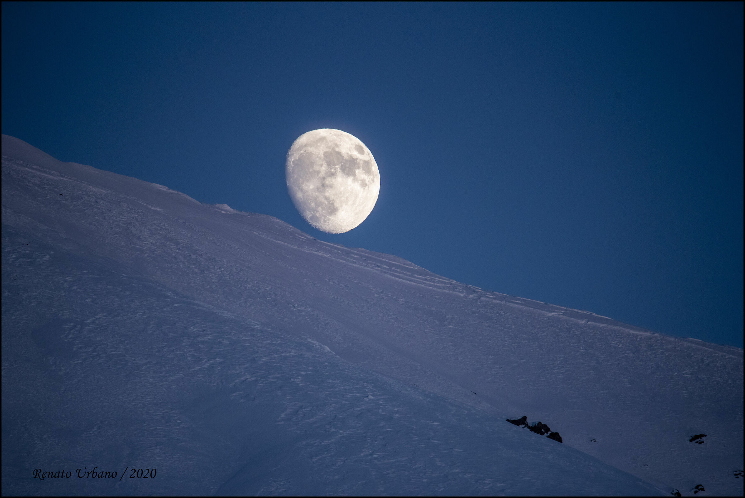 The moon emerges from the mountain