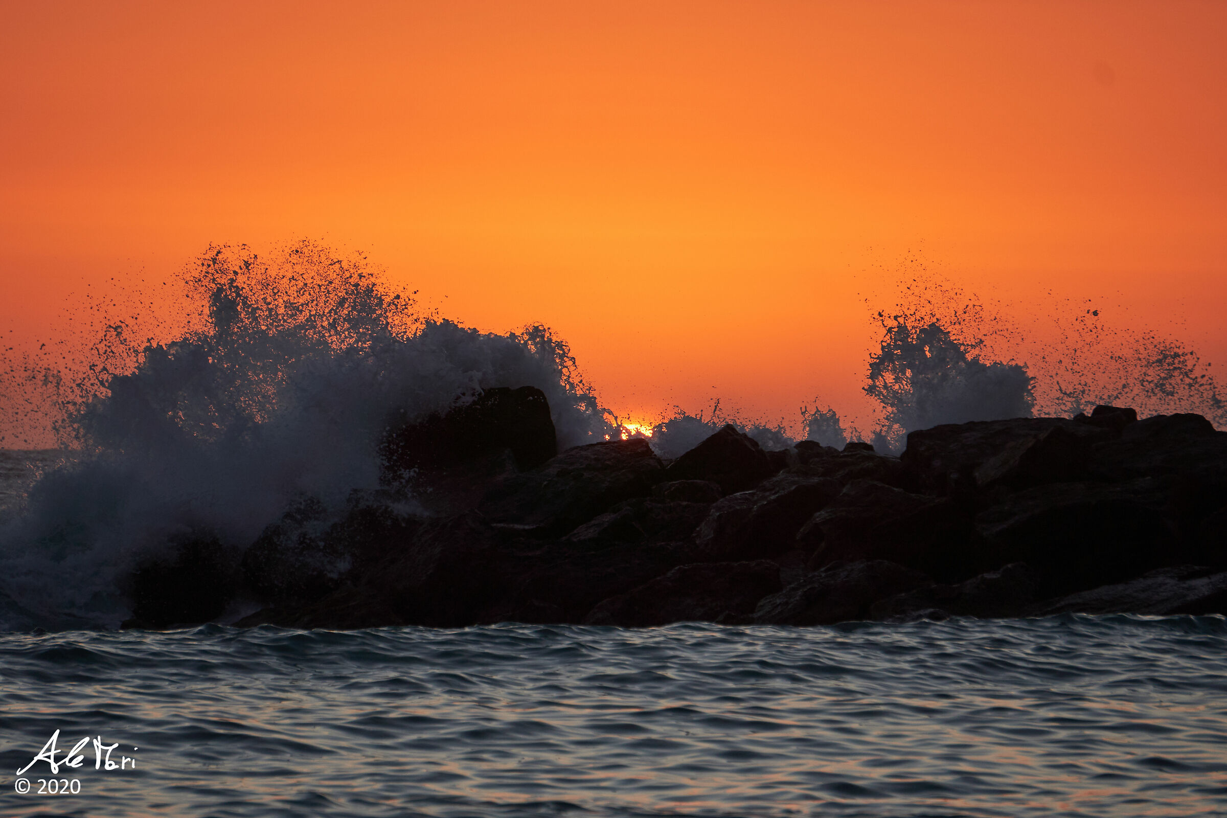 Sunset with rough sea over the rocks