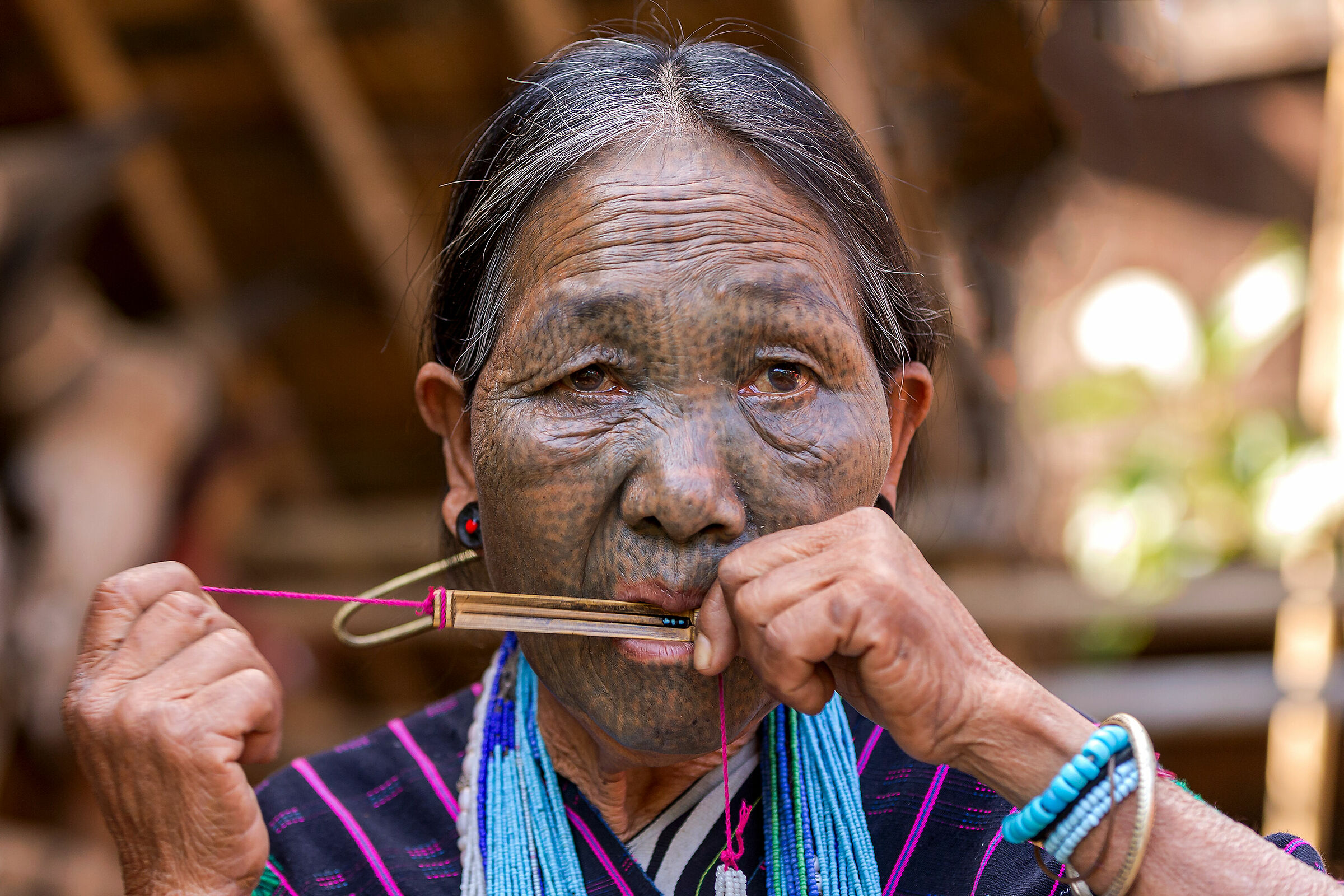 Chin woman playing jews harp