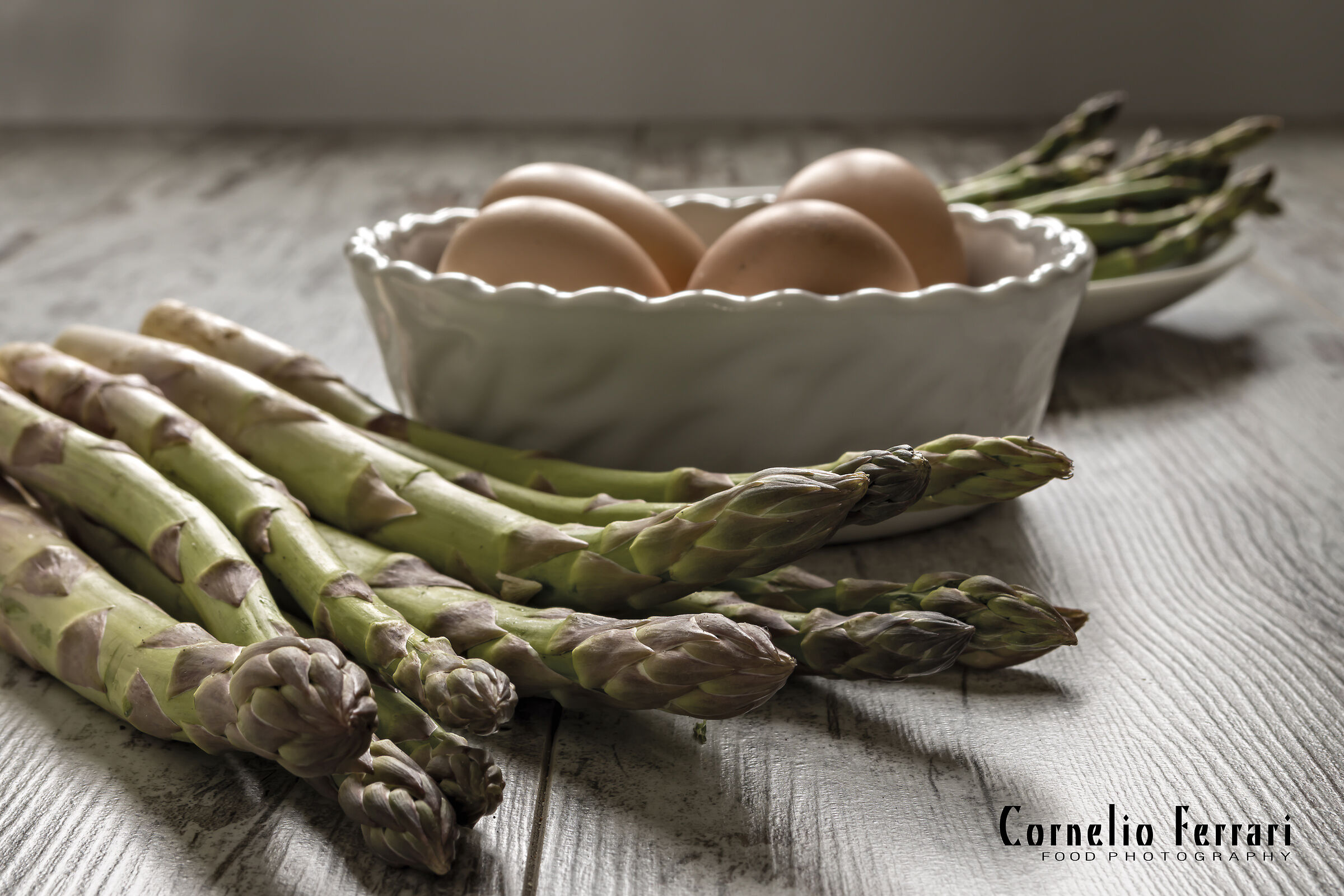 asparagi crudi sopra tavolo rustico con uova