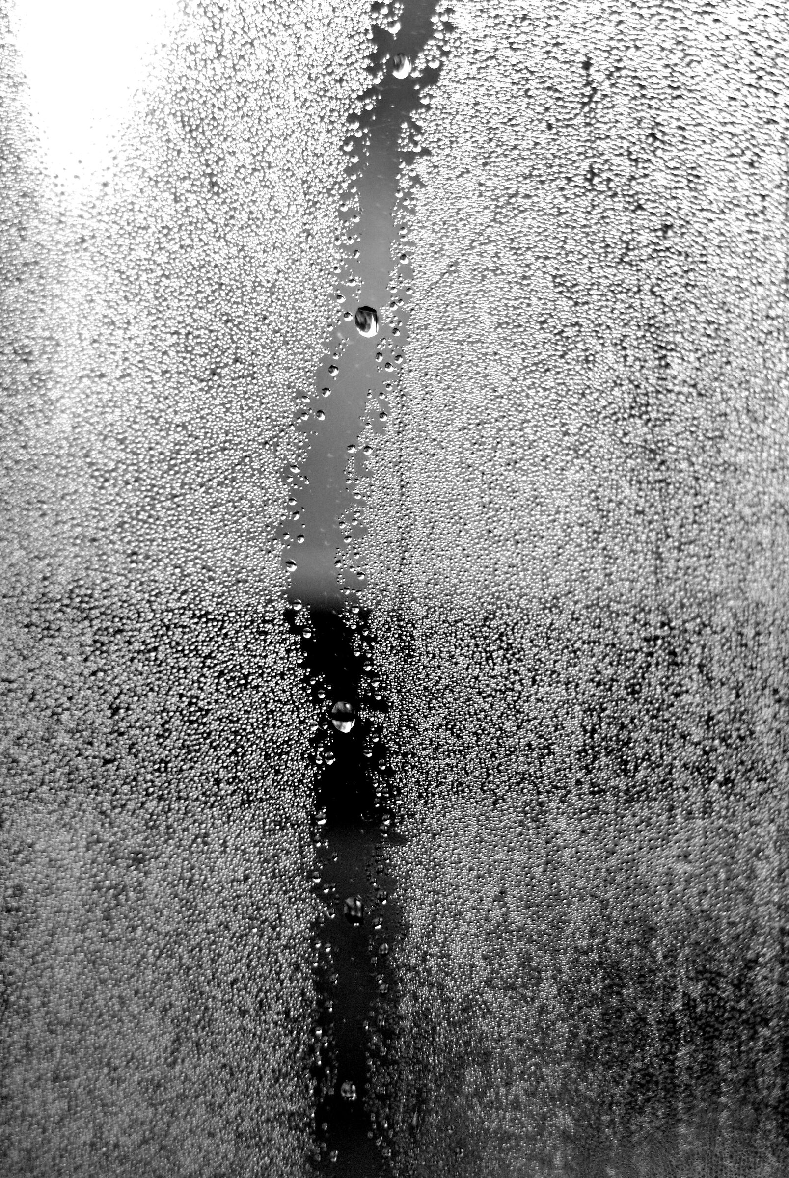 Drop descending on damp glass