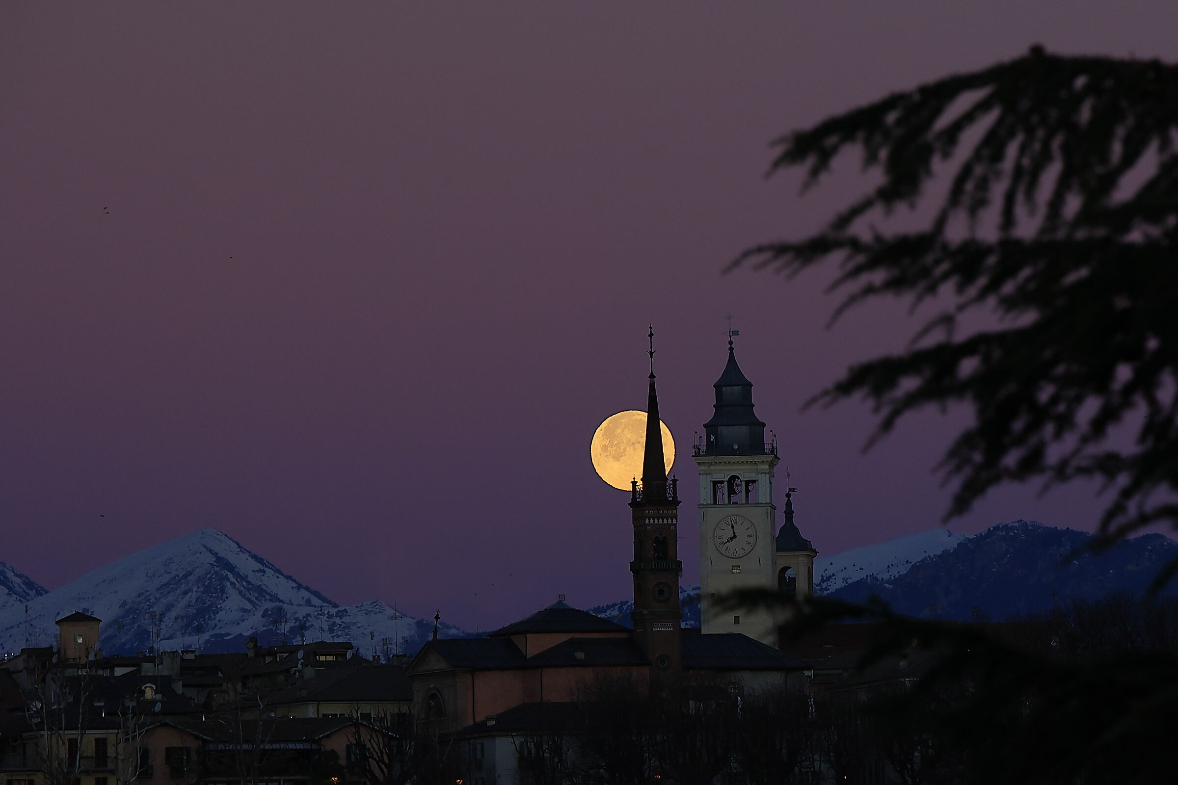 Luna timida dietro la torre civica di Cuneo