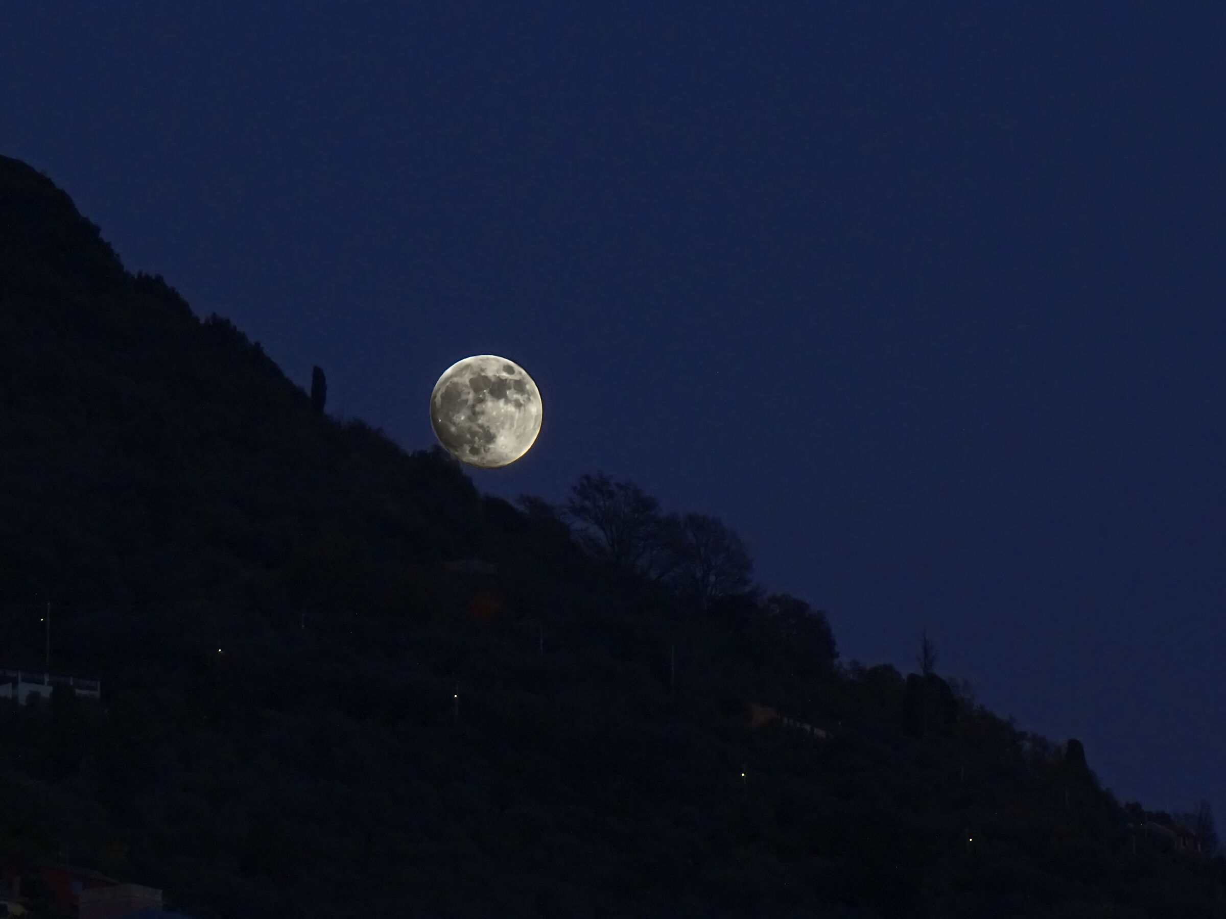 The moon rises from the hill