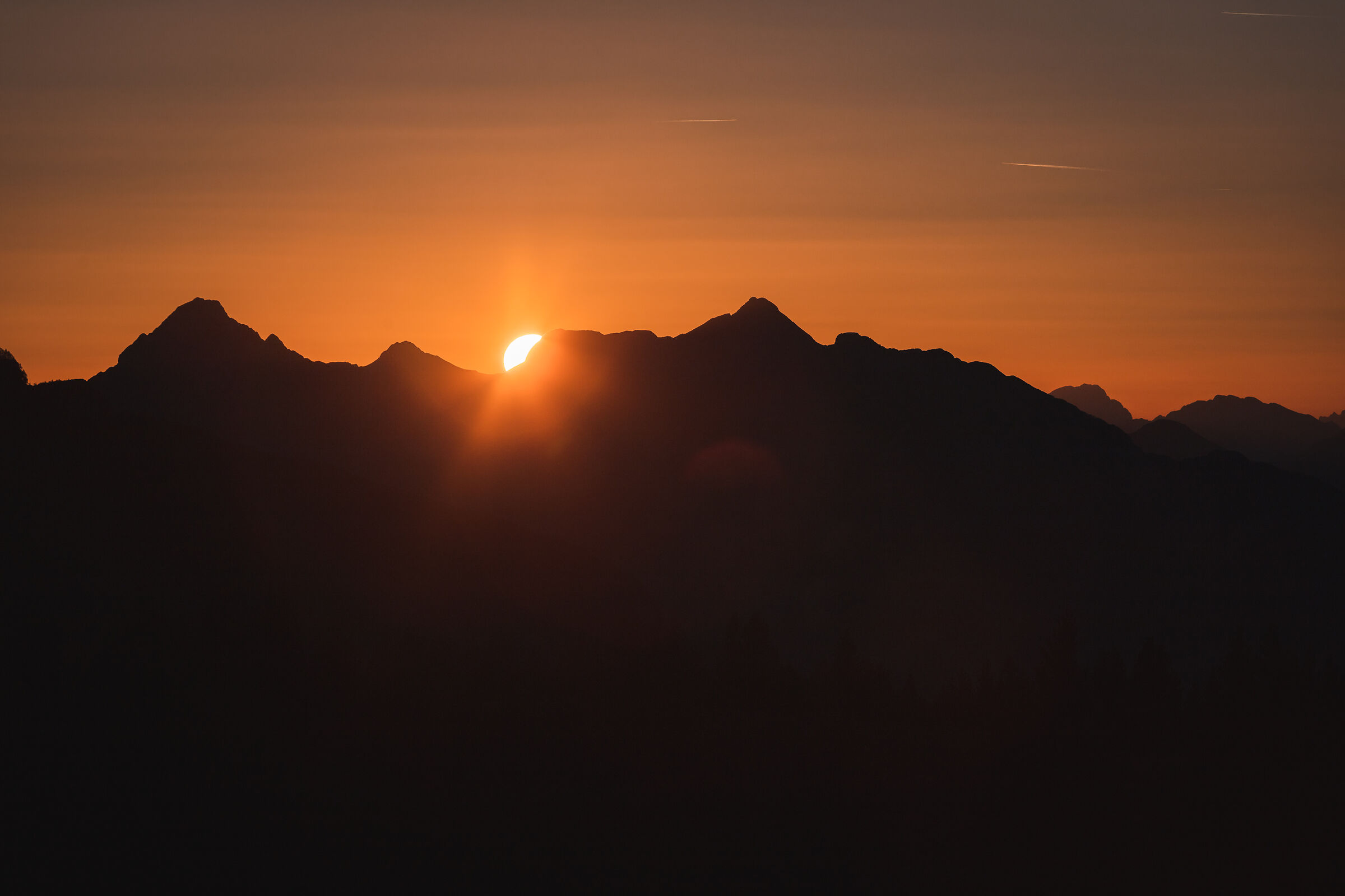 The sun hides behind the Friulian ridges