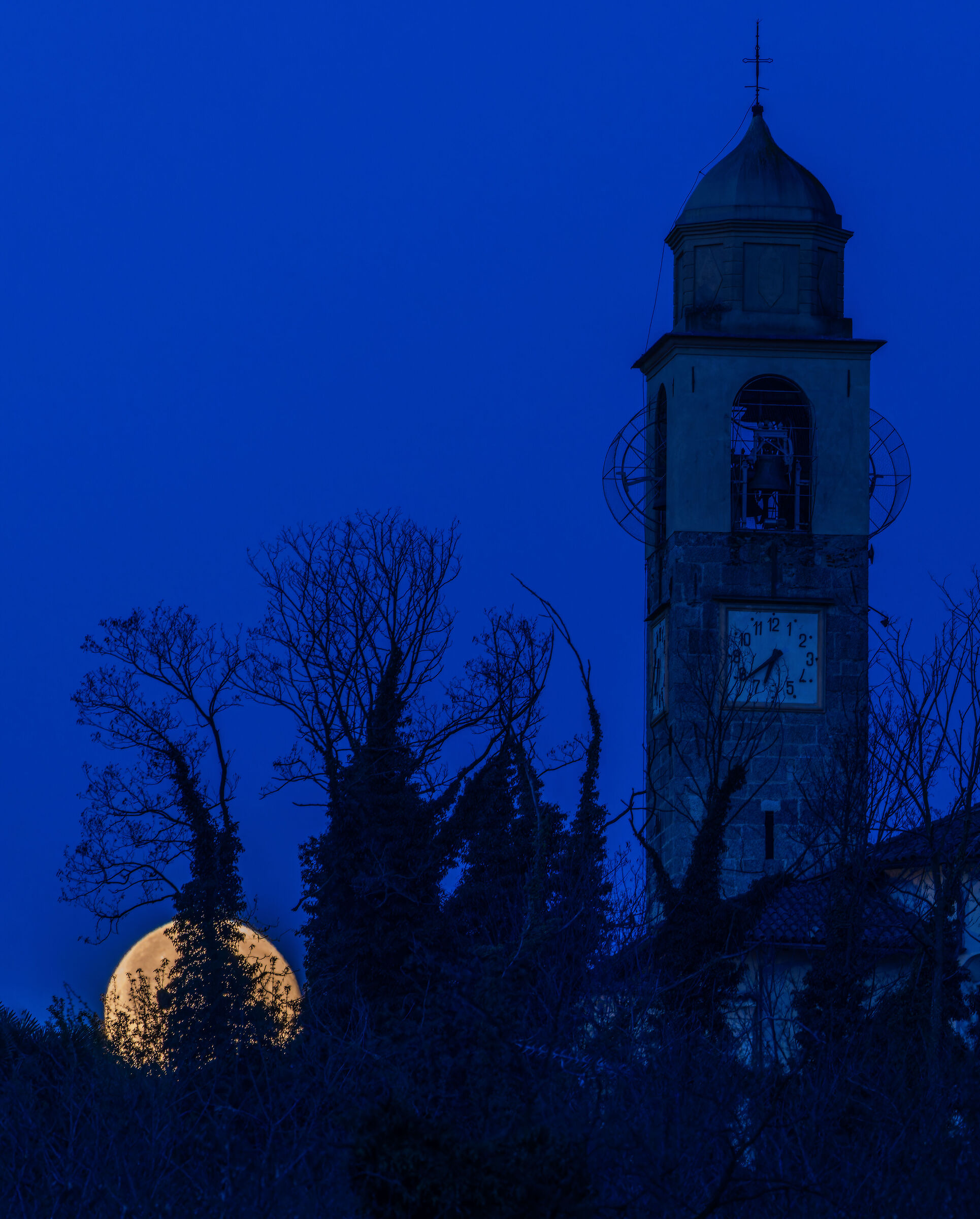 The moon sets behind the church of Dormelletto