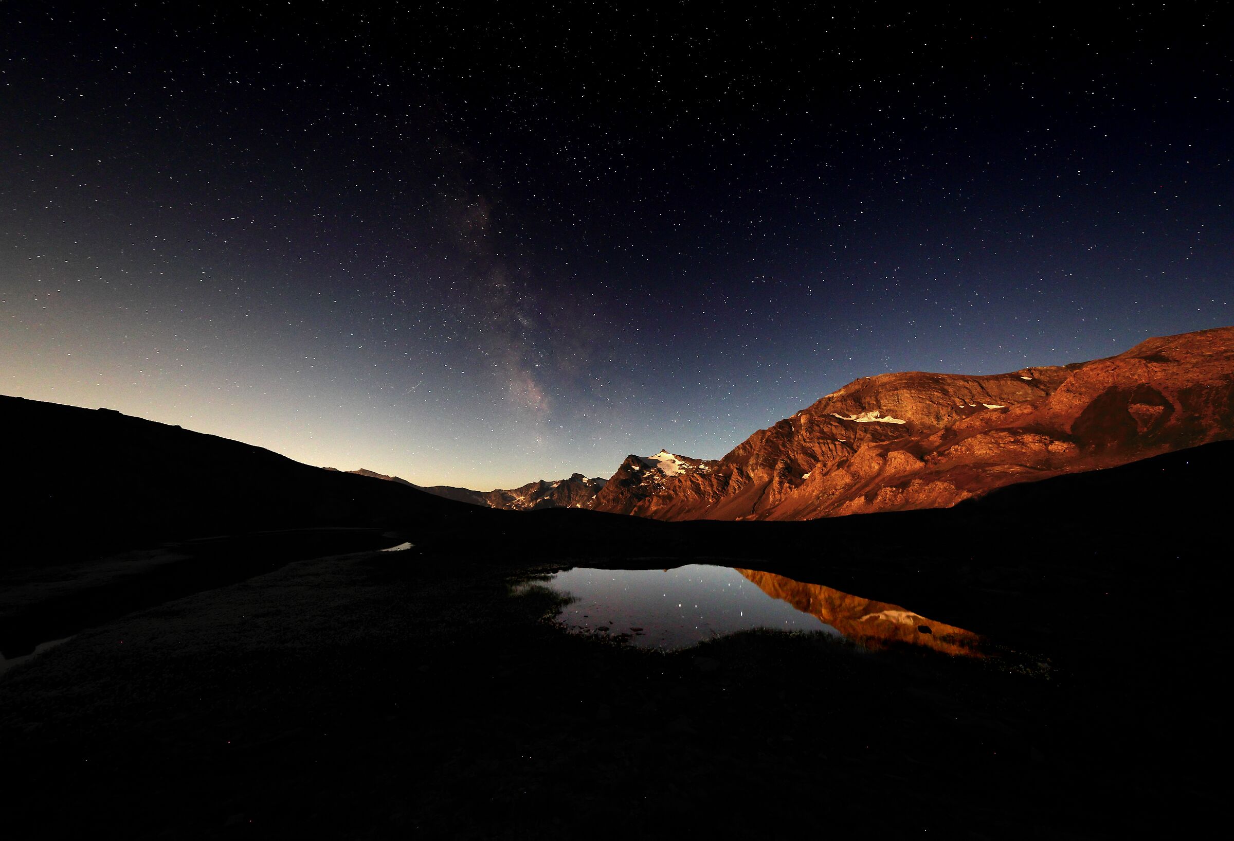 The Milky Way with the full moon illuminating the mountains