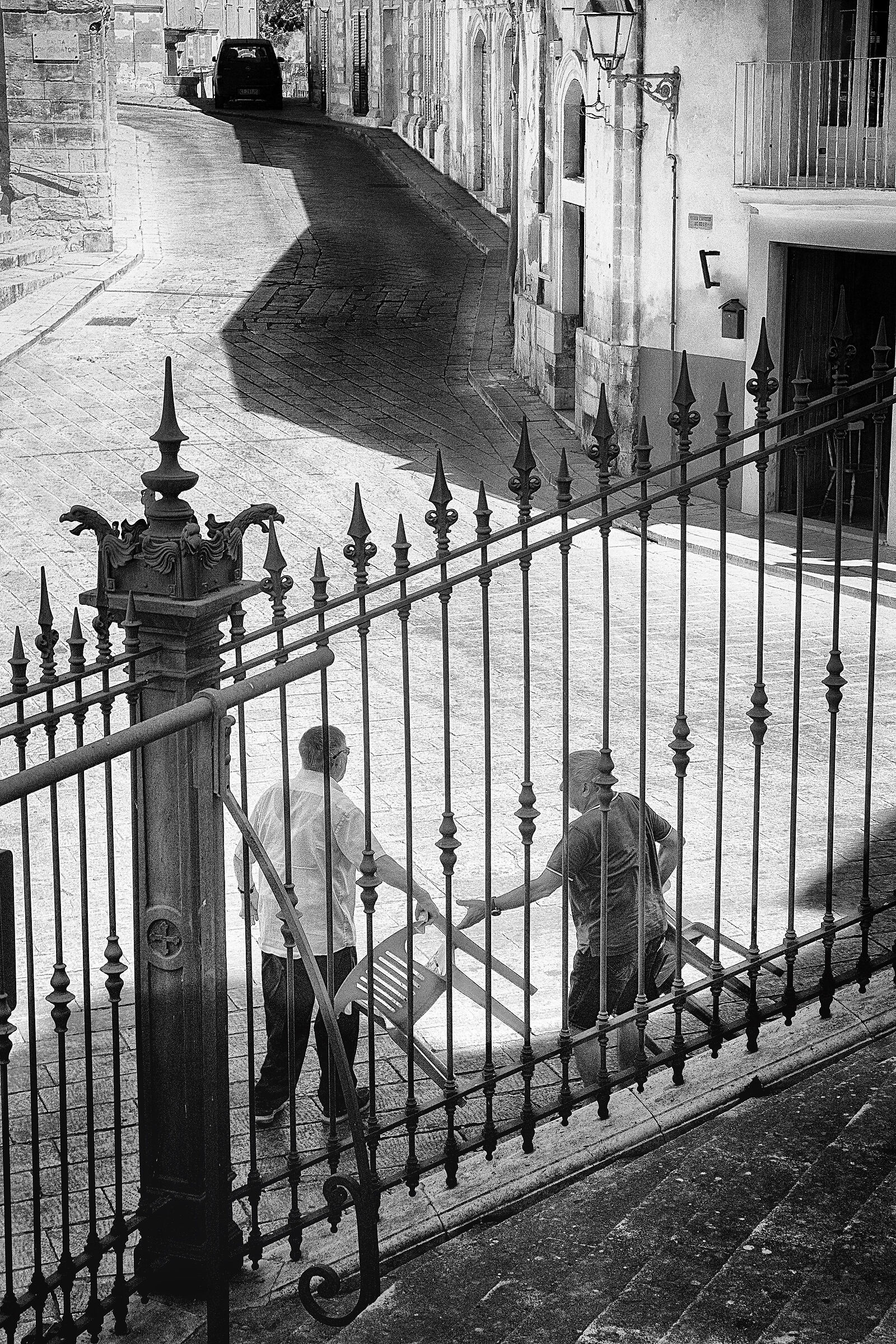 Street-side elders with plastic chair - Ragusa Ibla.
