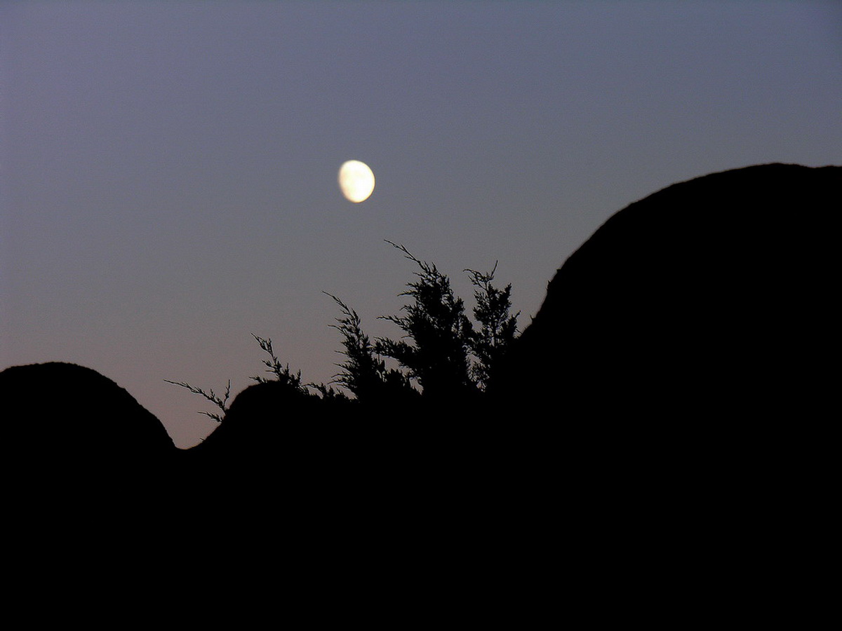 The moon rises from the mountain