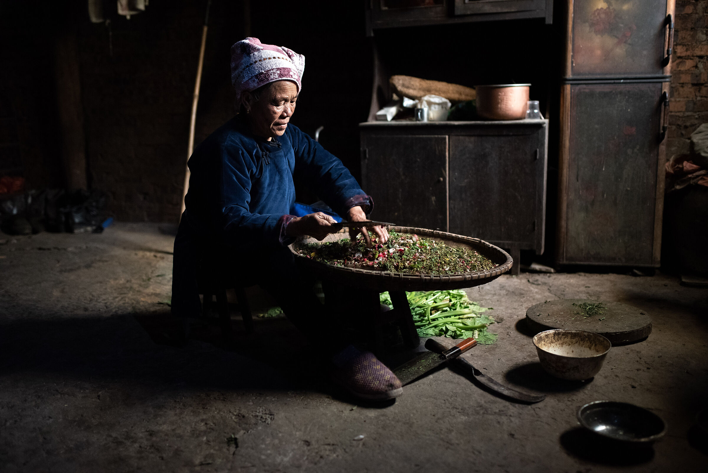 Elderly woman intent on chopping vegetables and vegetables