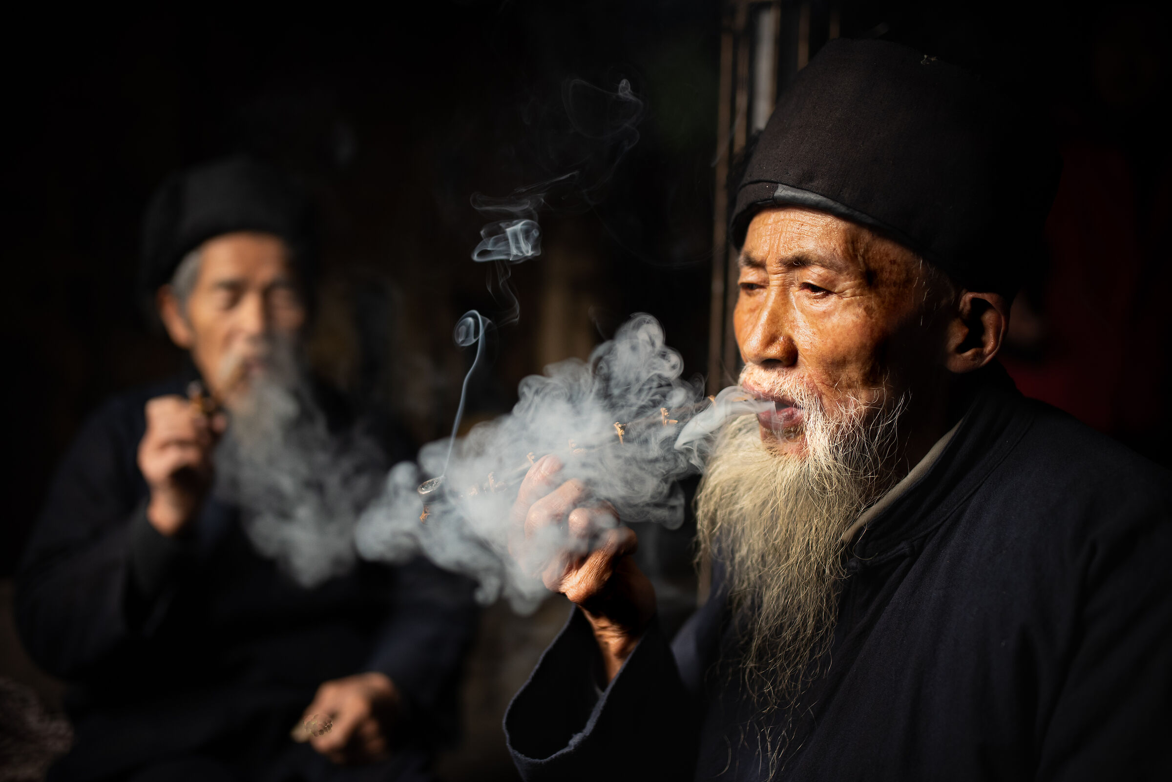 Two elderly people smoke pipe