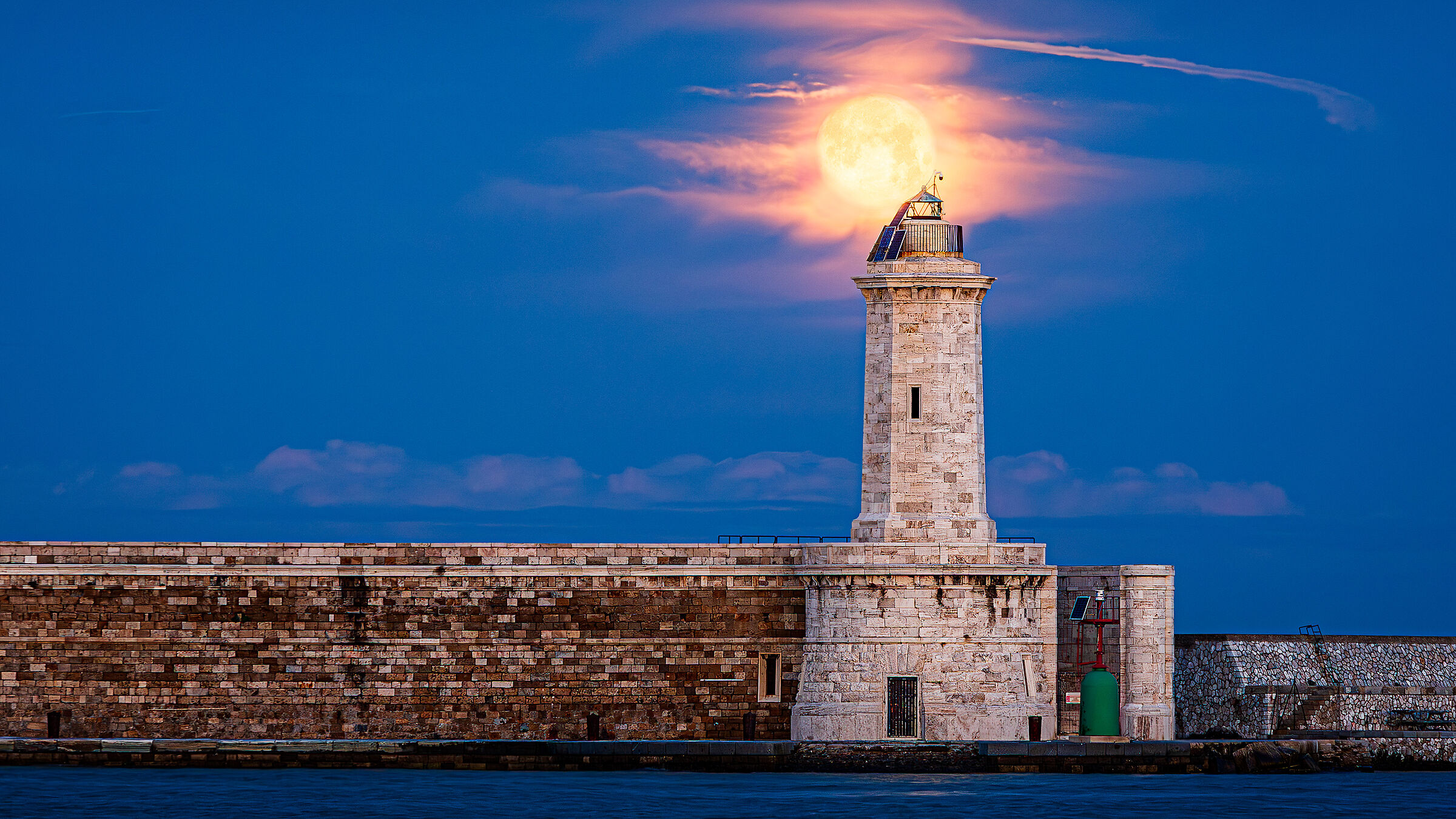 The full moon on the lighthouse of the curvilinear dam
