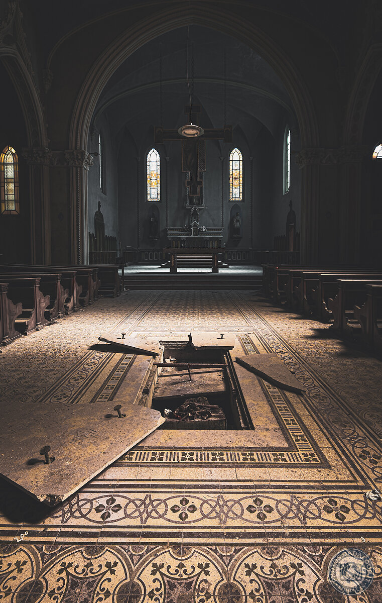Abandoned church with ornate floor and open trapdoor