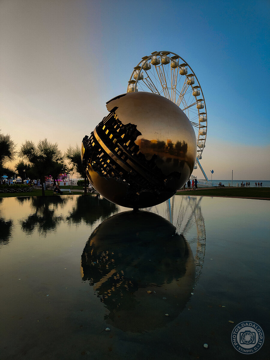 Metal sphere and Ferris wheel at sunset