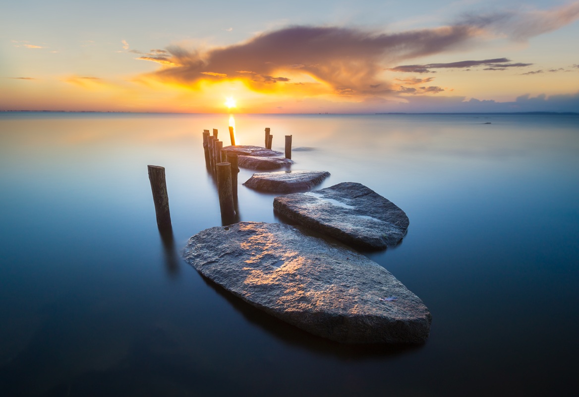 Alba, litorale, rocce e pali, contemplando il su