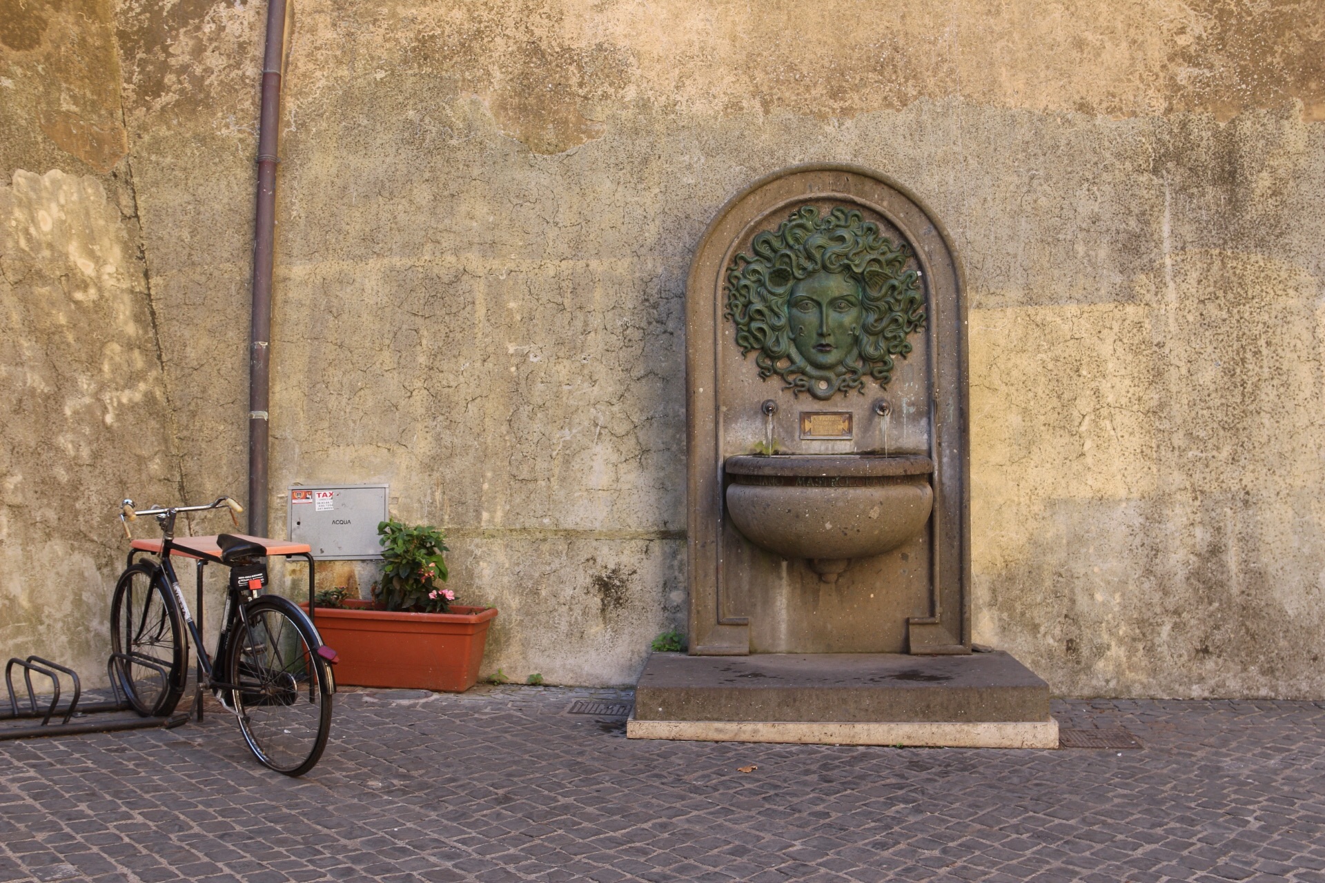 Fountain in the alley still working, the beat-up bike