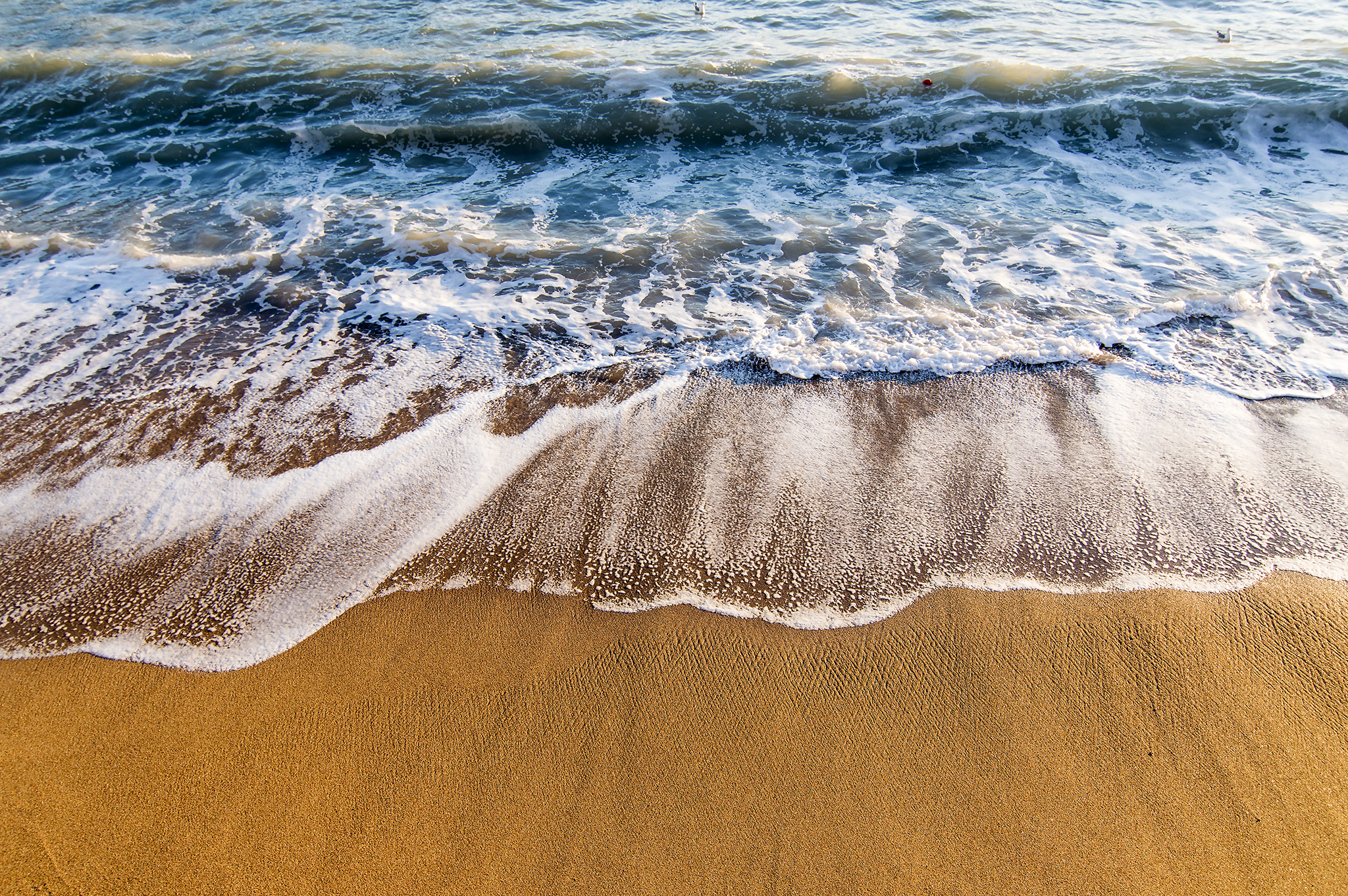 Le onde disegnano sulla battigia