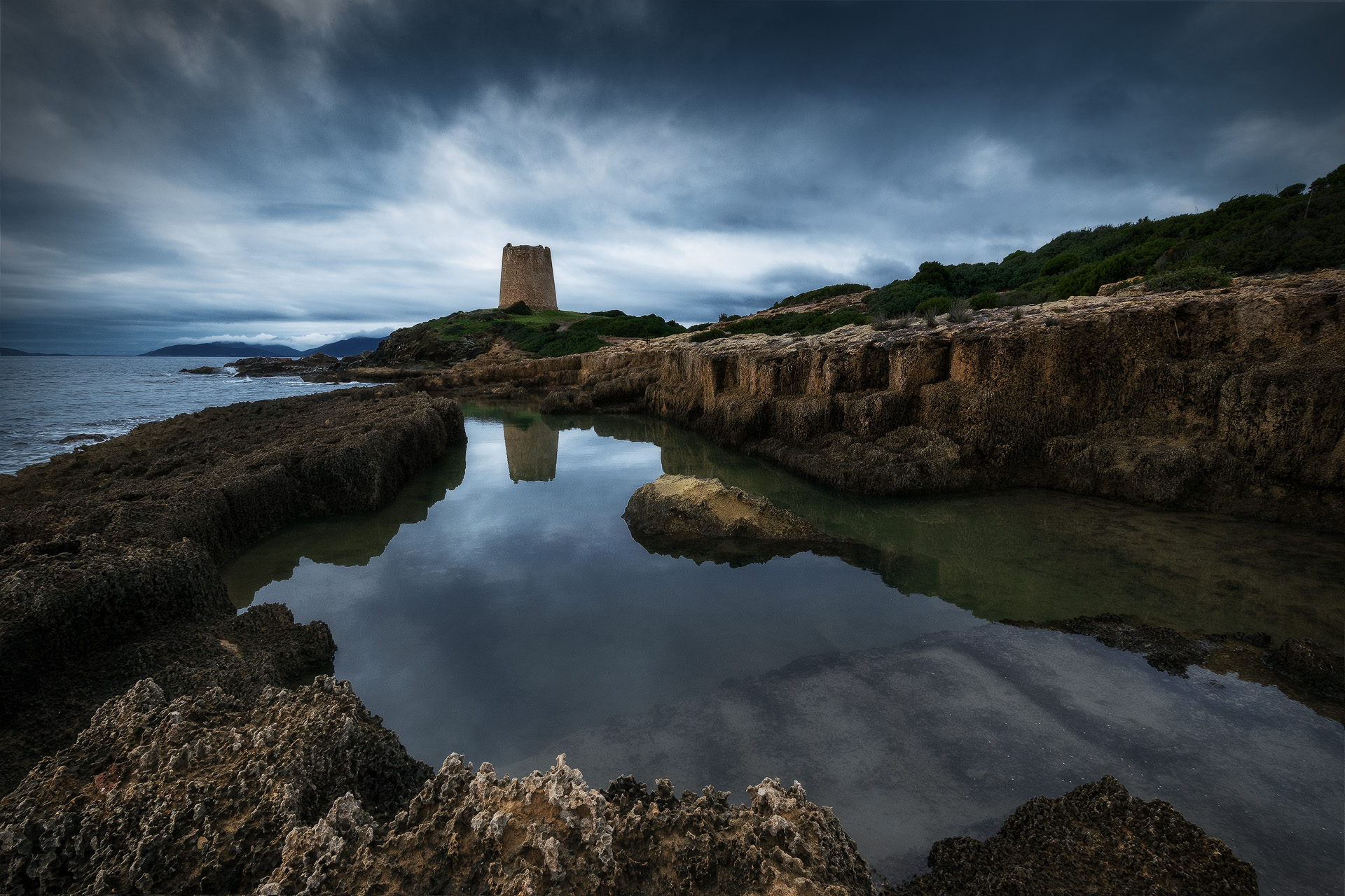 Torre di pixinnì riflessa in una piscina naturale