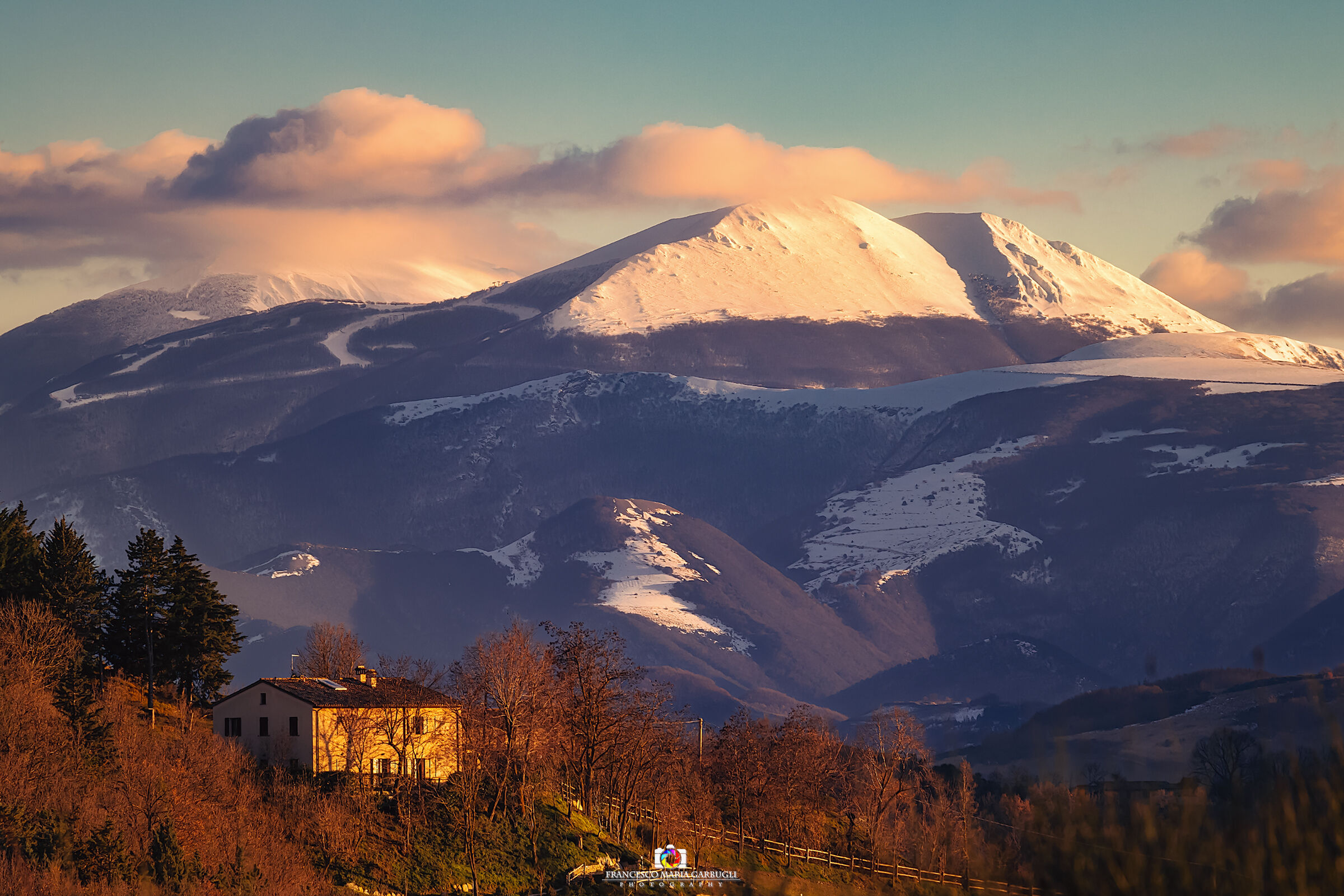 Farmhouse at sunset and snow-capped peaks