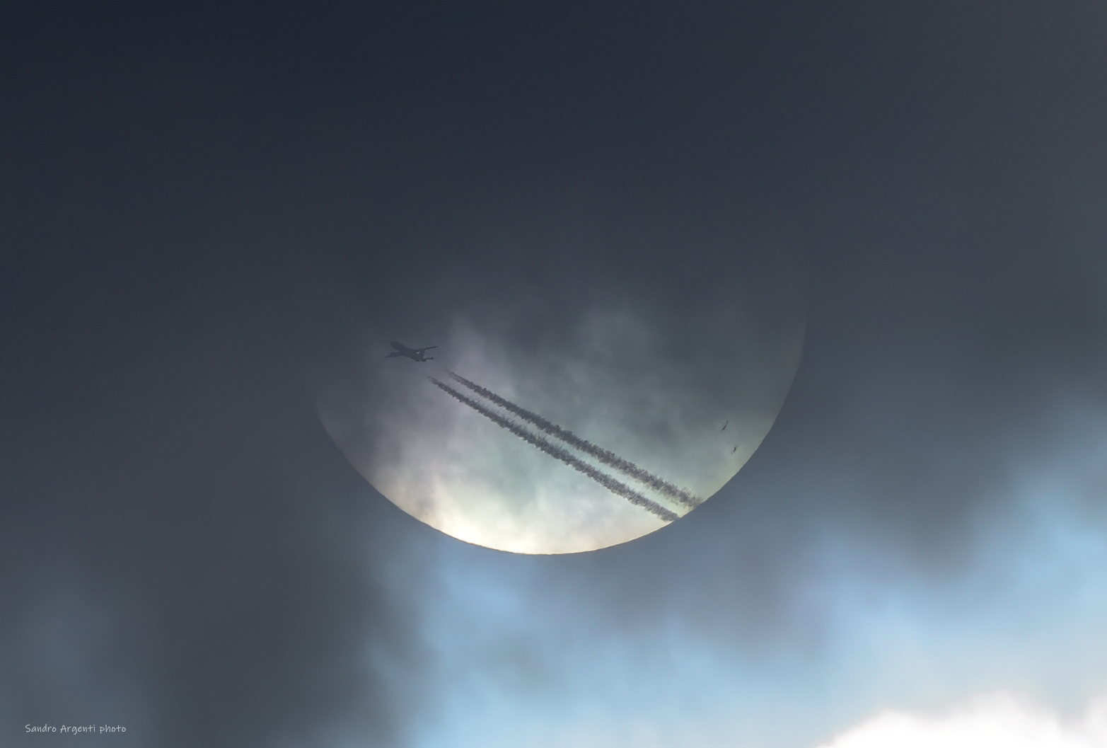 Scia di un aereo che attraversa il disco del Sole.