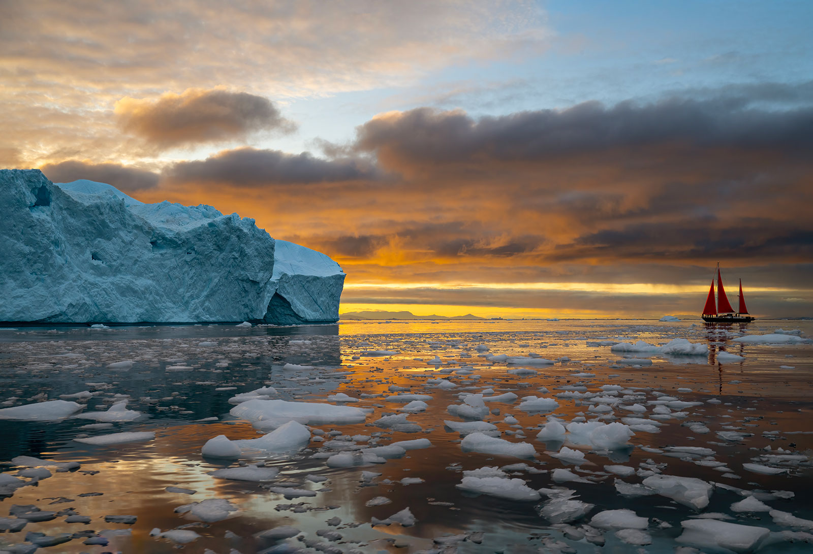Red sail among the icebergs of Disko Bay at sunset