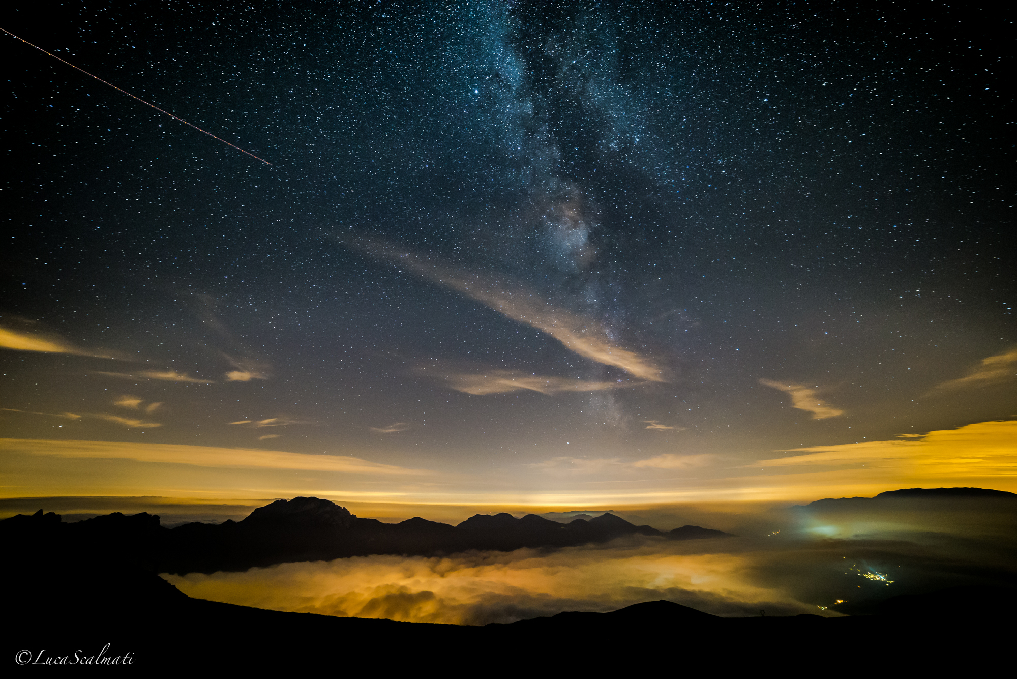 Milky Way that seems to arise from the lights of the valley